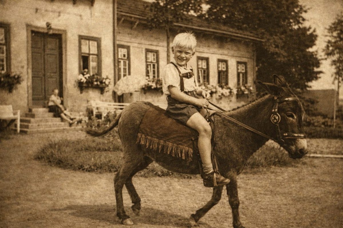 Kleiner Junge reitet auf einem Esel vor dem Herrenhaus Gut Buchenhof